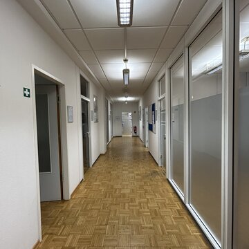 Ein Bild vom Flur. Links befinden sich geöffnete Türen zu Räumen.