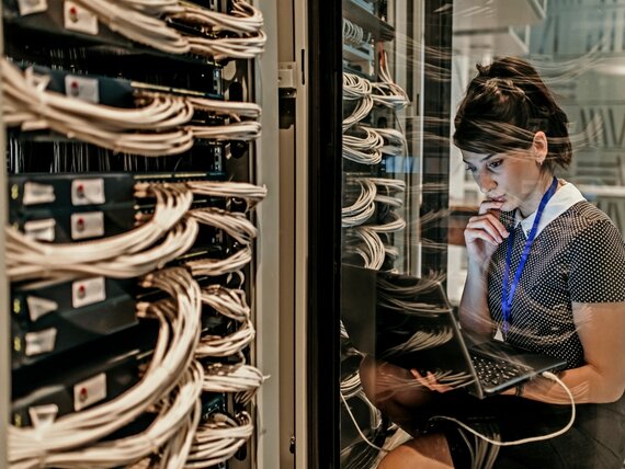 Eine Frau mit Laptop arbeitet an Server