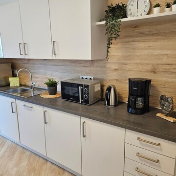 Küche mit mehreren Schränken, Wasserkocher, Kaffeemaschine, Mikrowelle und mehreren Pflanzen