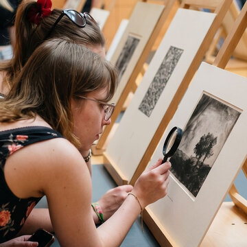 Schülerinnen betrachten Bilder in einer Ausstellung.