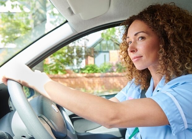 Eine junge Pflegerin im Auto, die zu ihren ambulanten Patienten und Patientinnen fährt