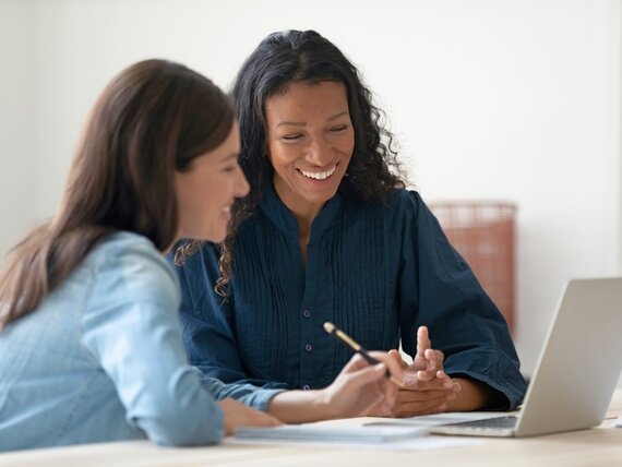Zwei Frauen arbeiten fröhlich am Laptop.