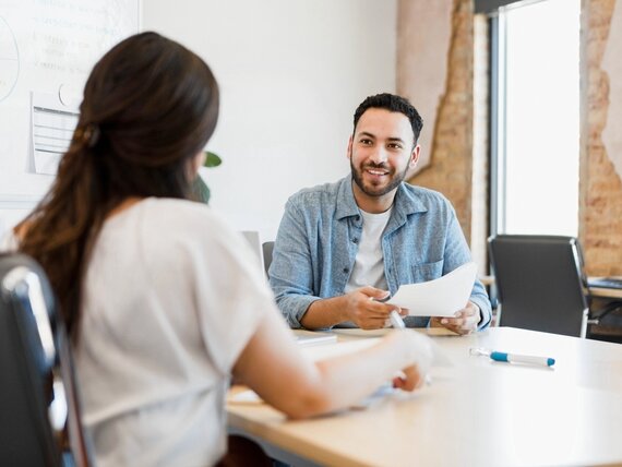 Ein Mann und eine Frau sitzen in einem Meetingraum und besprechen Unterlagen.