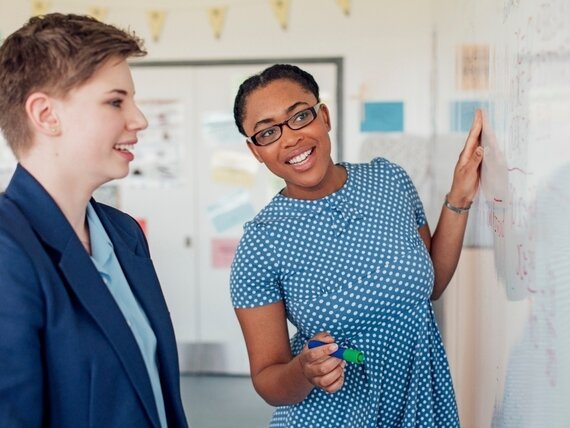 Zwei Frauen erarbeiten gemeinsam einen Plan am Whiteboard.