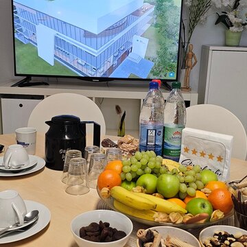 Gedeckter Tisch mit Kaffee, Obst und Plätzchen. Dahinter ein Bildschirm auf dem die digitale Lernumgebung zu sehen ist.