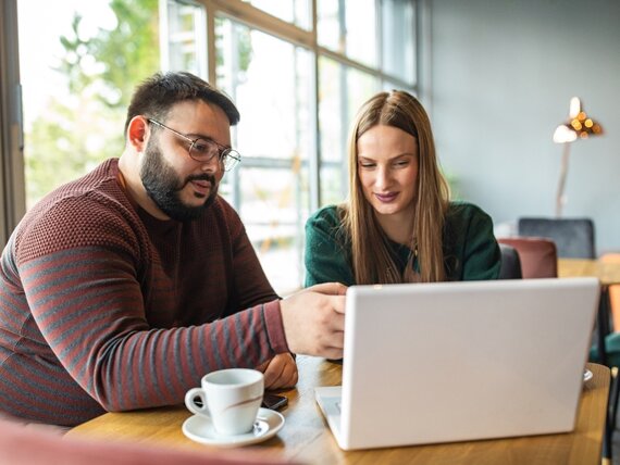 Ein Mann und eine Frau schauen sich gemeinsam etwas auf dem Laptop an.