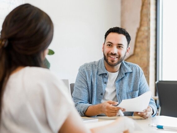 Ein Mann und eine Frau sitzen in einem Meetingraum und besprechen Unterlagen.