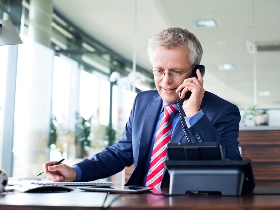 Ein Geschäftsmann im Büro telefoniert und macht sich Notizen