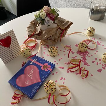 Genesungswünsche an unsere Regionalleiterin. Geschenke, Luftschlangen und Konfetti sowie Muffins und Blumen auf einem Tisch