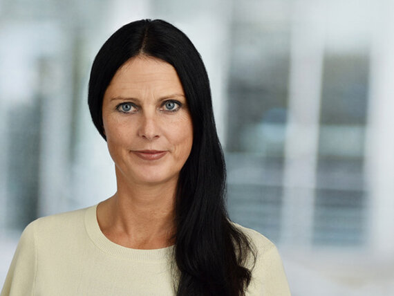 Unsere Coachin Melanie Elsner Eine Frau mit hellem Pullover und langen schwarzen Haaren, die ihr bildrechts über die Schulter hängen.
