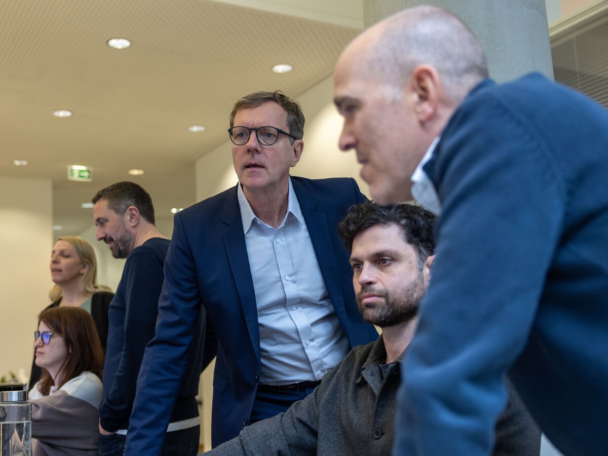 Sechs Personen arbeiten konzentriert in einem modernen Büro. Alle schauen konzentriert auf einen Computer Bildschirm.