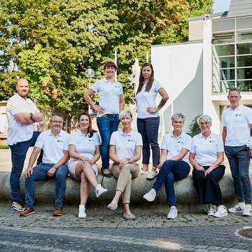 Team Region Bautzen-Görlitz, bestehend aus 9 Personen. Alle im weißen WBS GRUPPE T-Shirt am Brunnen vor einem Gebäude mit vielen großen Fenstern.