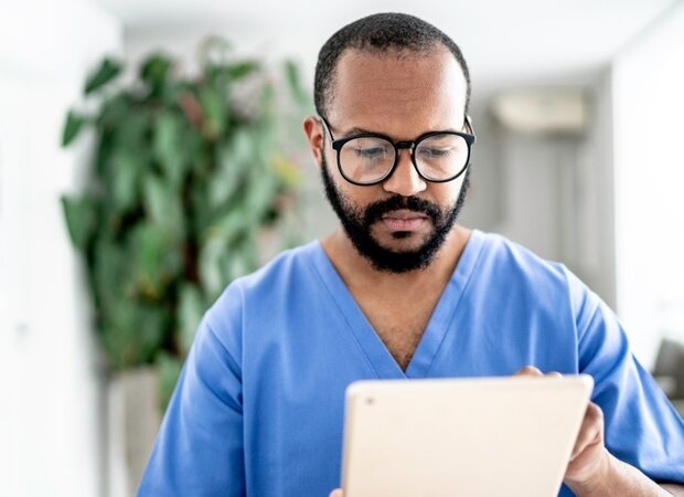 Ein Pfleger schaut sich etwas auf seinem Tablet an