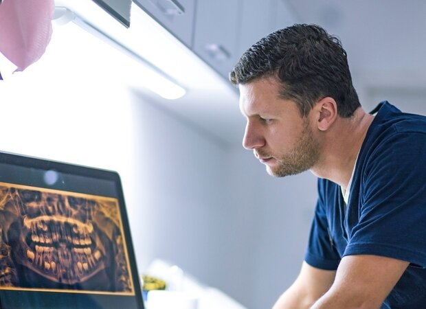 Ein Zahnarzt schaut sich eine Gebissaufnahme auf seinem Computer an