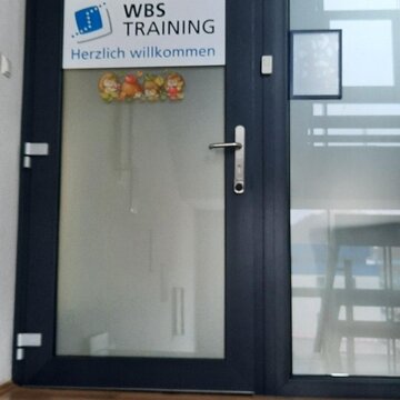 Gläserne Eingangstür mit Aufkleber WBS TRAINING und Herzlich willkommen.