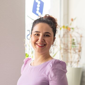 Das Bild zeigt Hatice Ilbasmis, Bildungsreferentin im Bereich Umschulungen bei WBS TRAINING. Sie lächelt herzlich, trägt ein fliederfarbenes Oberteil und steht vor einem hellen Hintergrund. Ihr freundliches Auftreten vermittelt Offenheit und Kompetenz
