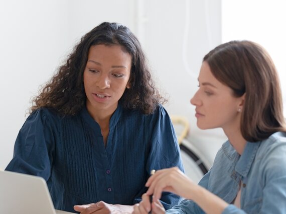 Zwei Frauen besprechen etwas konzentriert am Laptop.