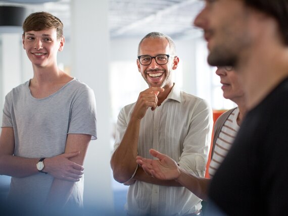 Eine Gruppe Männer und Frauen unterhalten sich fröhlich.