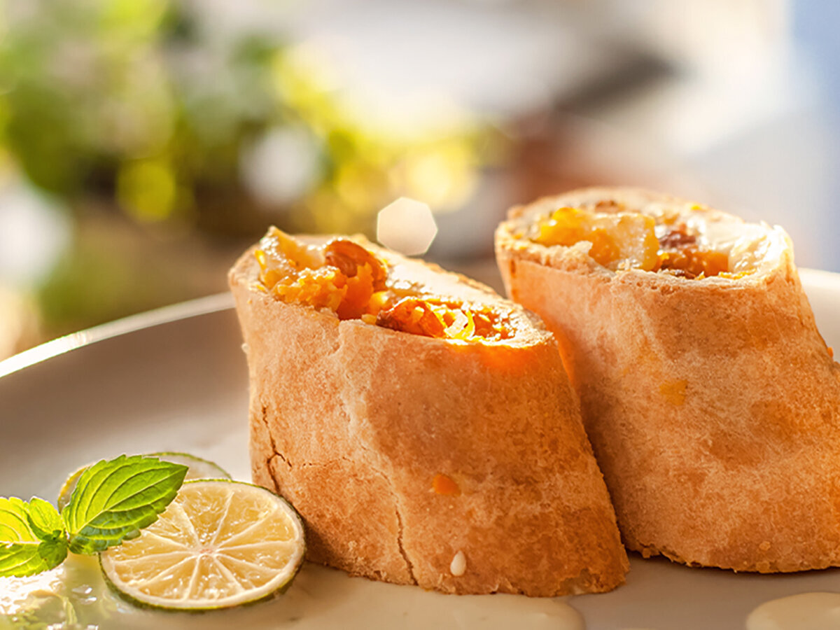 Osterrezept Möhrenstrudel zwei Stück Möhrenstrudel auf einem Teller mit Limettenscheiben und Minze als Dekoration.