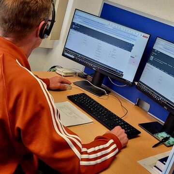 Ein Teilnehmer sitzt an seinem Arbeitsplatz und trägt ihr Headset während er in der virtuellen Lernumgebung lernt.