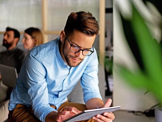 Ein Mann schaut konzentriert auf sein Tablet.