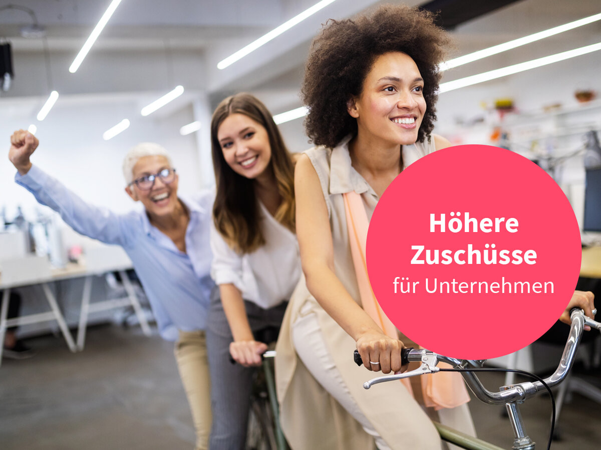 Drei Frauen lächelnd und motiviert im Büro mit Störer. 