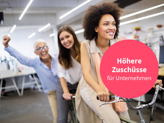 Drei Frauen lächelnd und motiviert im Büro mit Störer. 