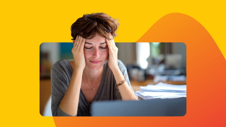 Eine Frau sitzt angespannt vor einem Laptop, Kopf auf den Händen abgestützt, versucht sich zu konzentrieren