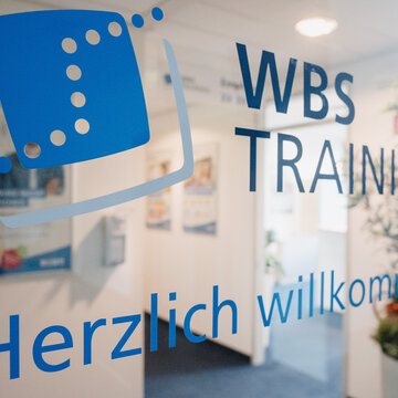 Glastür mit Aufklebern der WBS TRAINING und einem "Herzlich Willkommen"