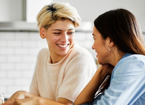 2 Frauen sitzen in einer Küche und arbeiten gemeinsam an einem Laptop.
