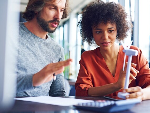 Ein Mann und eine Frau im Büro analysieren ein Windrad-Modell.