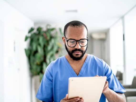 Ein Pfleger schaut sich etwas auf seinem Tablet an