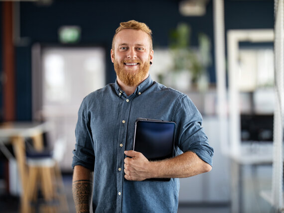 Junger Mann mit Jeanshemd und Kalendermappe in der Hand.