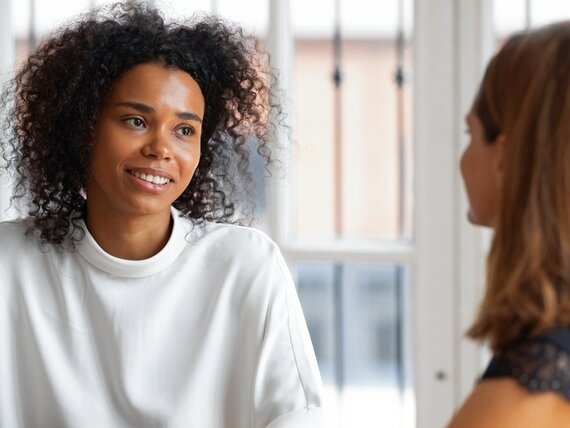 Zwei Frauen unterhalten sich und eine davon macht sich Notizen.