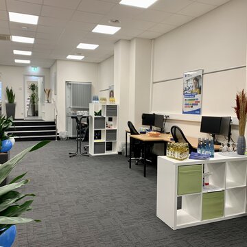 Schulungsraum mit Arbeitsbereichen, Regalen und Grünpflanzen.