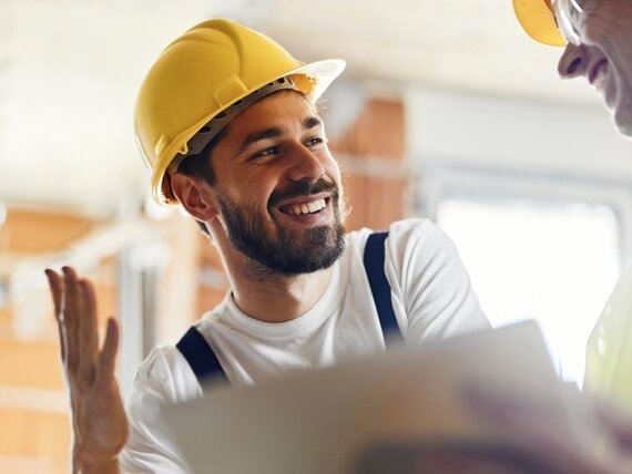 Zwei Männer mit Schutzhelmen unterhalten sich auf einer Baustelle