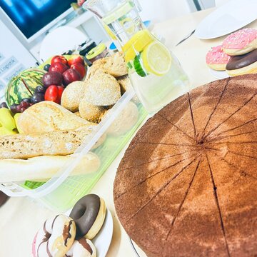 Ein gedeckter Tisch mit Kuchen, Donuts, Baguette und Obst.
