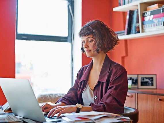 Eine Frau arbeitet am Laptop in einem farbenfrohen Büroraum.