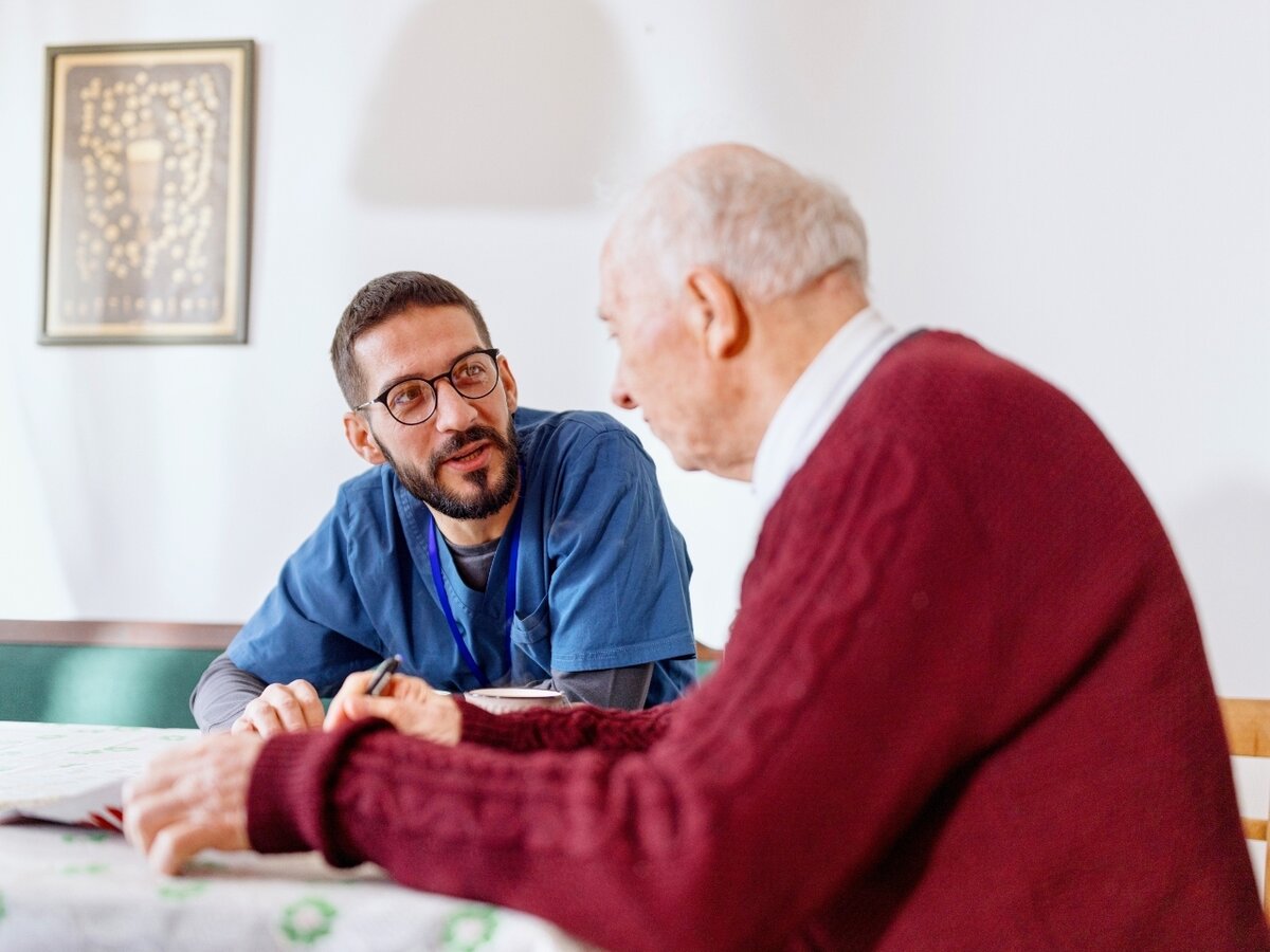Ein ambulanter Pfleger unterhält sich mit einem Senioren