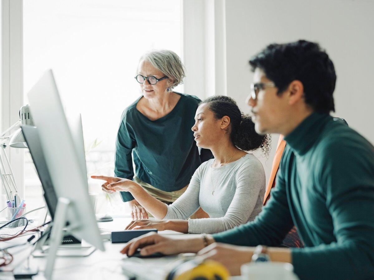 Kolleginnen und Kollegen arbeiten gemeinsam an ihren Computern im Büro.
