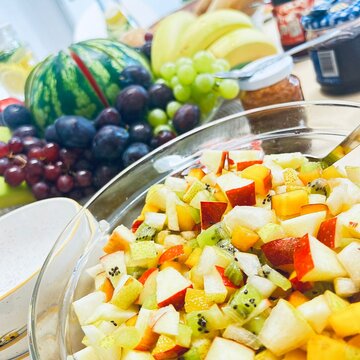 Bild von einem gedeckten Tisch mit Obststalat, einem Obstkorb sowie verschiedenen Aufstrichen und Baguette.