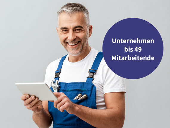 Mann in Latzhose und Tablet lächelt in die Kamera