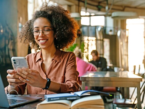 Eine Frau im Café mit ihrem Smartphone in der Hand.