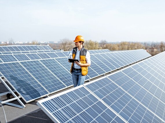 Ein Mann mit Tablet und Plänen schaut sich Photovoltaik Anlagen an.