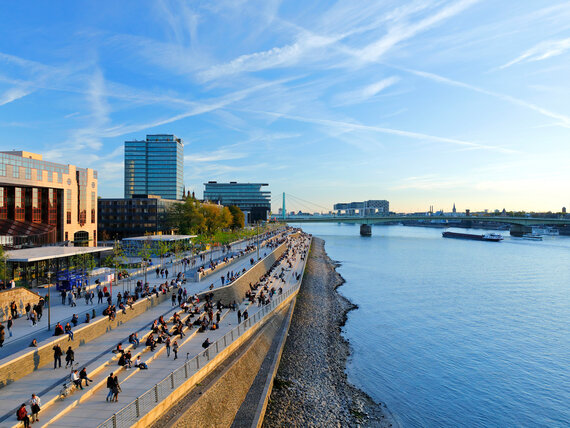 Menschen am Rheinufer in Köln bei Abendsonne.
