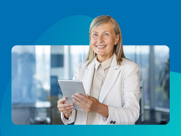 Frau mit grauen Haaren in Anzug hält Tablet in der Hand.