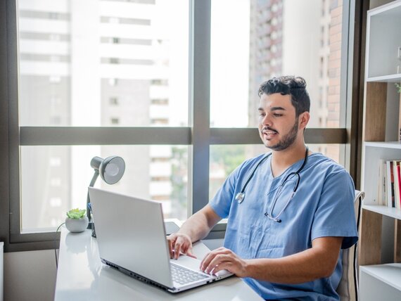 Ein Arzt sitzt in seinem Büro und arbeitet am Computer