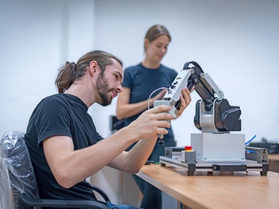Ein junger Mann arbeitet an einem Roboterarm