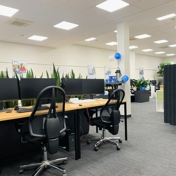 Gemütlicher Schulungsraum mit mehren Arbeitsbereichen, die alle mit 2 Bildschirmen, Tastatur und headset ausgestattet sind.