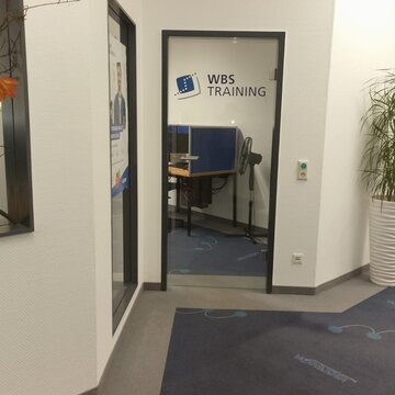 Eingangsbereich, Glastür zum Schulungsraum. Rechts daneben eine Topfpflanze.
